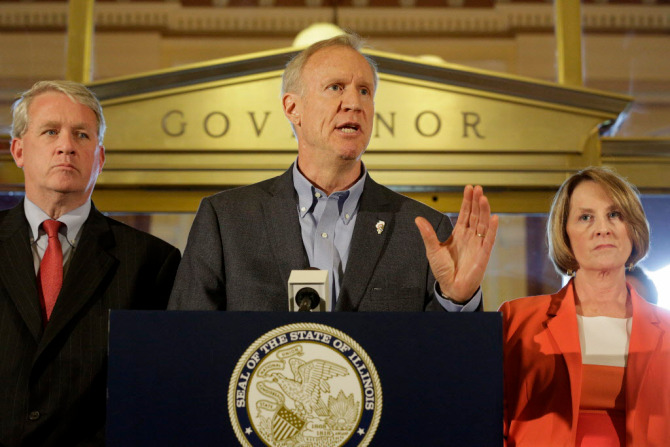 Illinois Gov. Bruce Rauner speaks to reporters in front of his office at the Illinois State Capitol Thursday, June 30, 2016, in Springfield, Ill. Illinois lawmakers approved a partial spending plan Thursday that would ensure schools stay open another year and give colleges and human service programs funding for six months, a rare bipartisan accomplishment but one that won't end the yearlong gridlock on a full budget. Illinois House Minority Leader Jim Durkin, R-Western Springs, left, and Illinois Senate Minority Leader Christine Radogno, R-Lemont, right, look on. (AP Photo/Seth Perlman) ORG XMIT: ILSP119