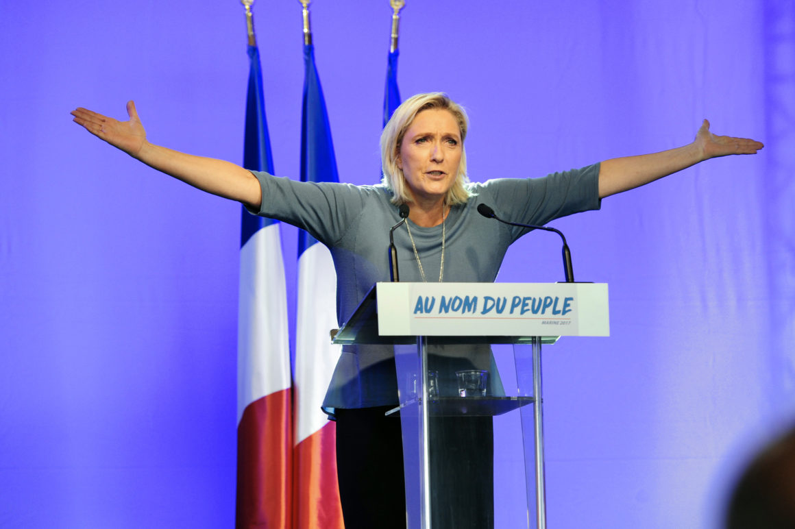TOPSHOT - French far-right Front National (FN) party's President, Marine Le Pen, gestures as she delivers a speech on stage during the FN's summer congress in Frejus, southern France, on September 18, 2016.  Marine Le Pen's slogan reading "In the name of the [French] people" is seen on the rostrum. / AFP / Franck PENNANT        (Photo credit should read FRANCK PENNANT/AFP/Getty Images)